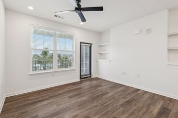 A room with a ceiling fan and a window overlooking a balcony at The Junction at Rockledge Apartments, Rockledge, FL